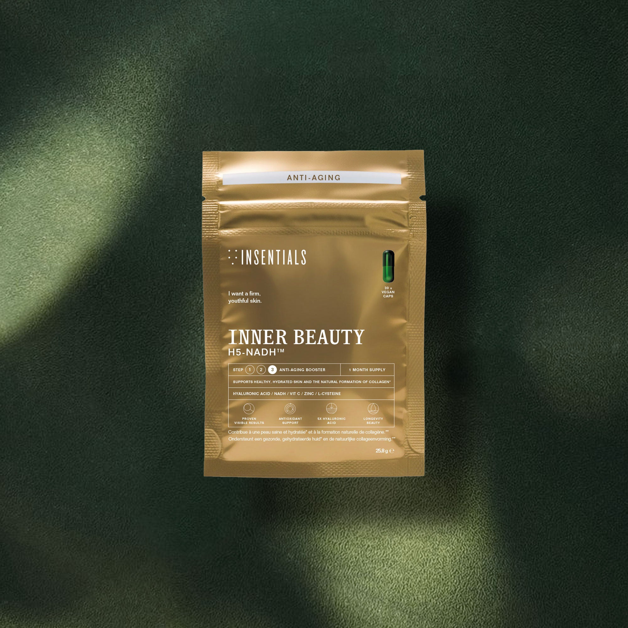 Een gouden zakje met het opschrift „Insentials Inner Beauty H5-NADH™” (huidverjonging op celniveau) ligt op een donkergroen, gestructureerd oppervlak; zonlicht valt op een deel van de verpakking en roept een gevoel op van een langdurige gezondheid van de huid en verhoogde celenergie.