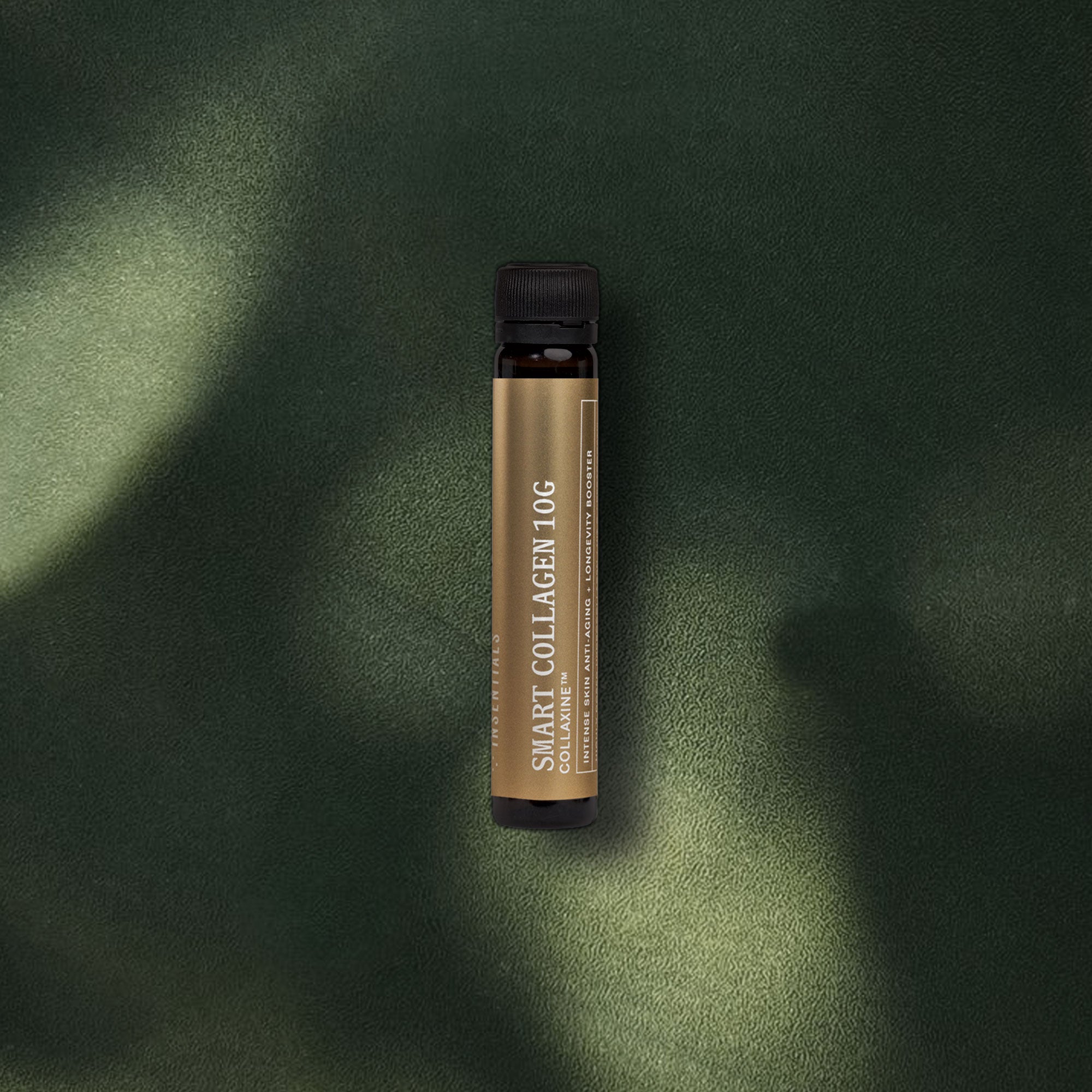 Een bruin flesje met het etiket „Smart Collagen Shot 10 g (collageen 10 g)” van Insentials staat op een donkergroen oppervlak met structuur, badend in zacht zonlicht en schaduwen – waardoor deze krachtige collageenshot voor huidelasticiteit extra goed tot zijn recht komt.