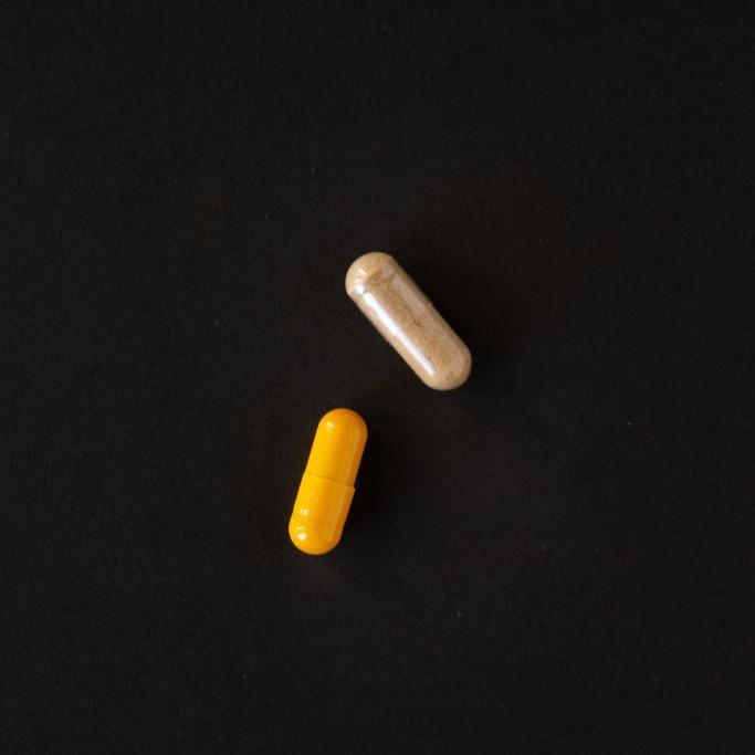 Twee capsules, een gele en een beige, op een zwart oppervlak, symboliseren RainPharma&