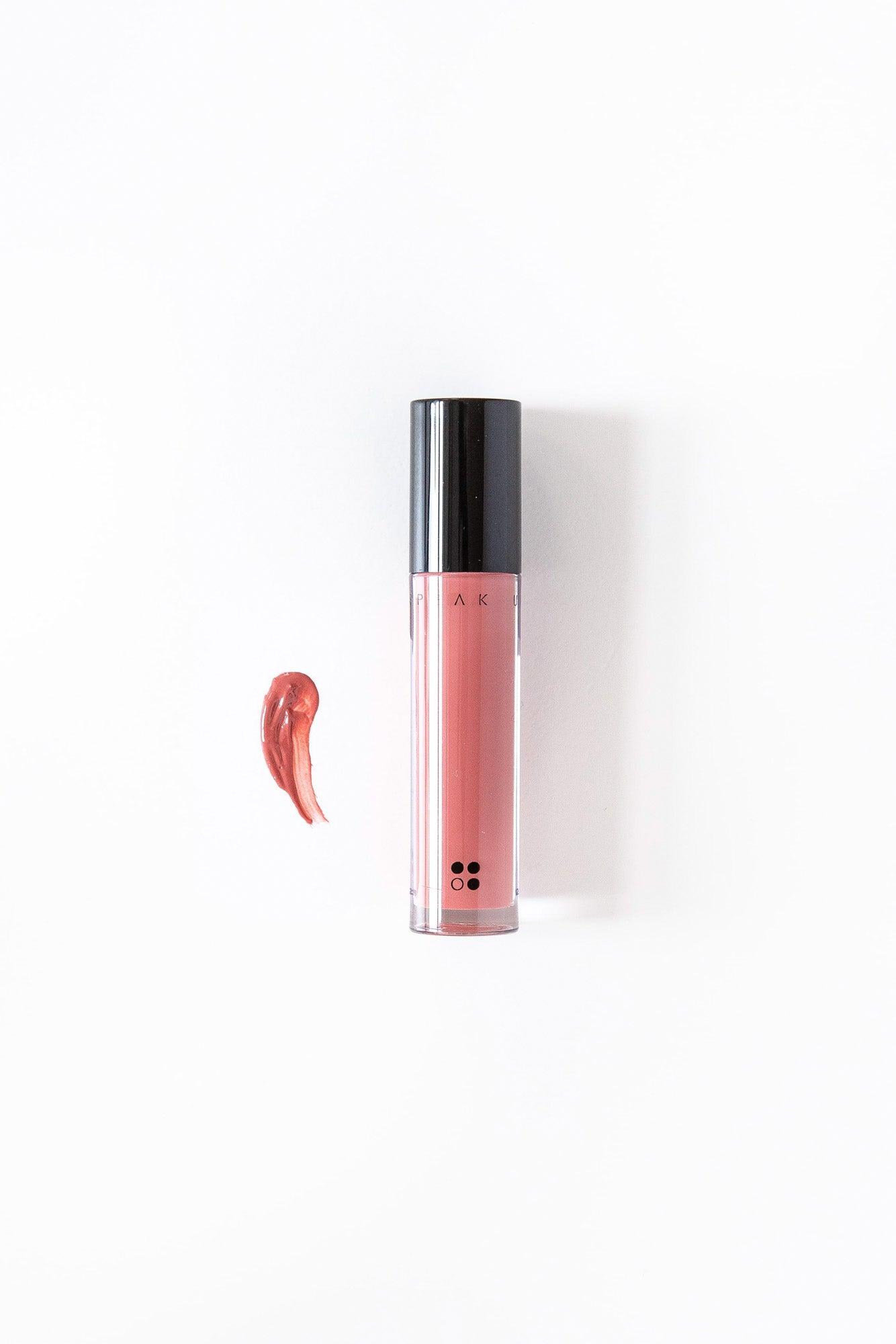 Speak Up - Natural Lip Tint van RainPharma wordt geleverd in een tube met een zwarte dop en een nauwkeurige applicator, afgebeeld naast een uitstrijkje van de glanzend gepigmenteerde formule op een witte achtergrond.