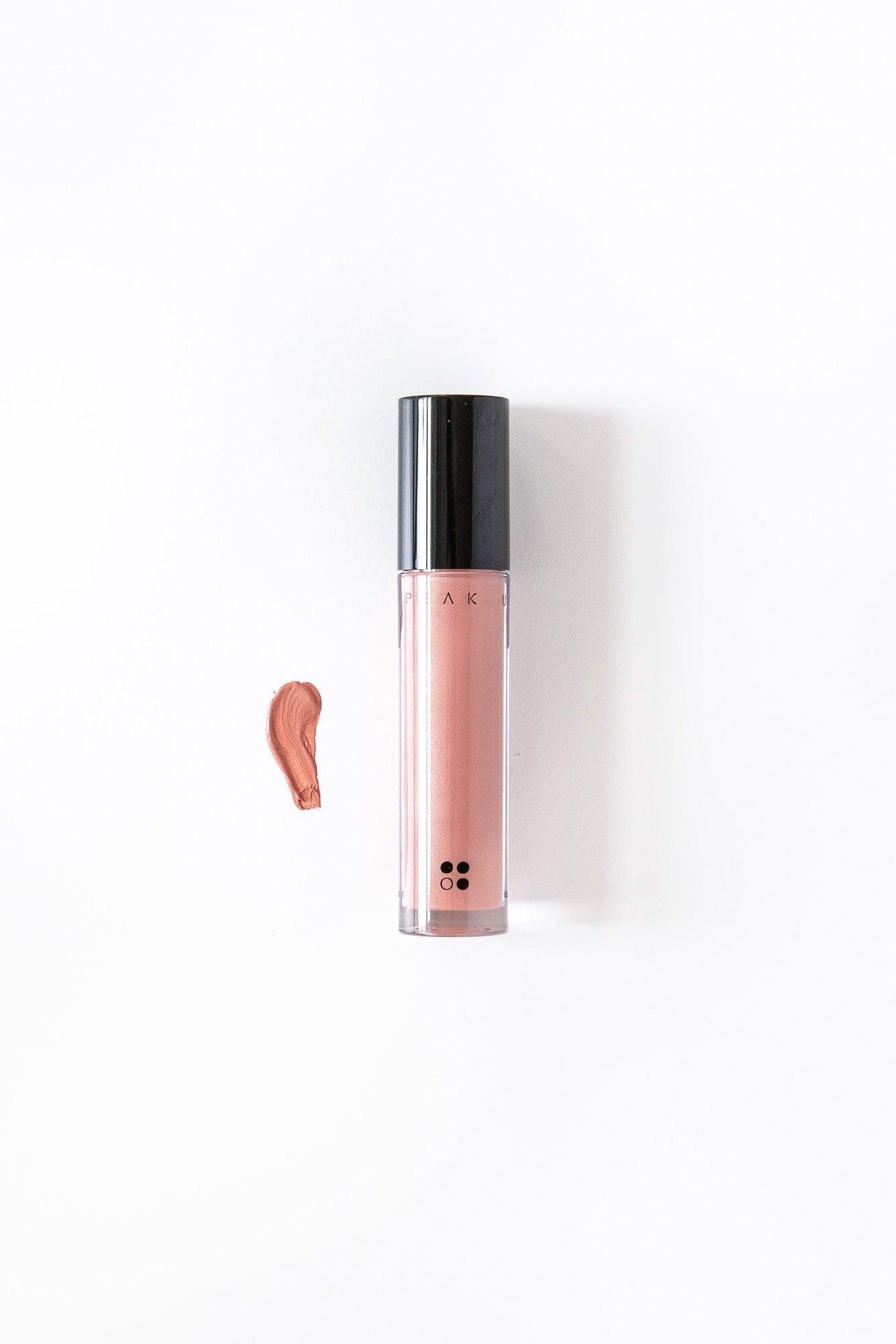 Speak Up - Natural Lip Tint van RainPharma, met zijn glanzend gepigmenteerde finish en levendige nude roze tint, wordt weergegeven op een witte achtergrond met een zwarte dop en een kleurenstaal ernaast.