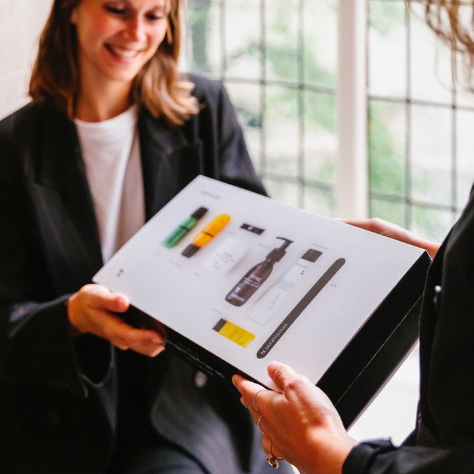 Twee personen wisselen een RainPharma Handverzorging Set - It&