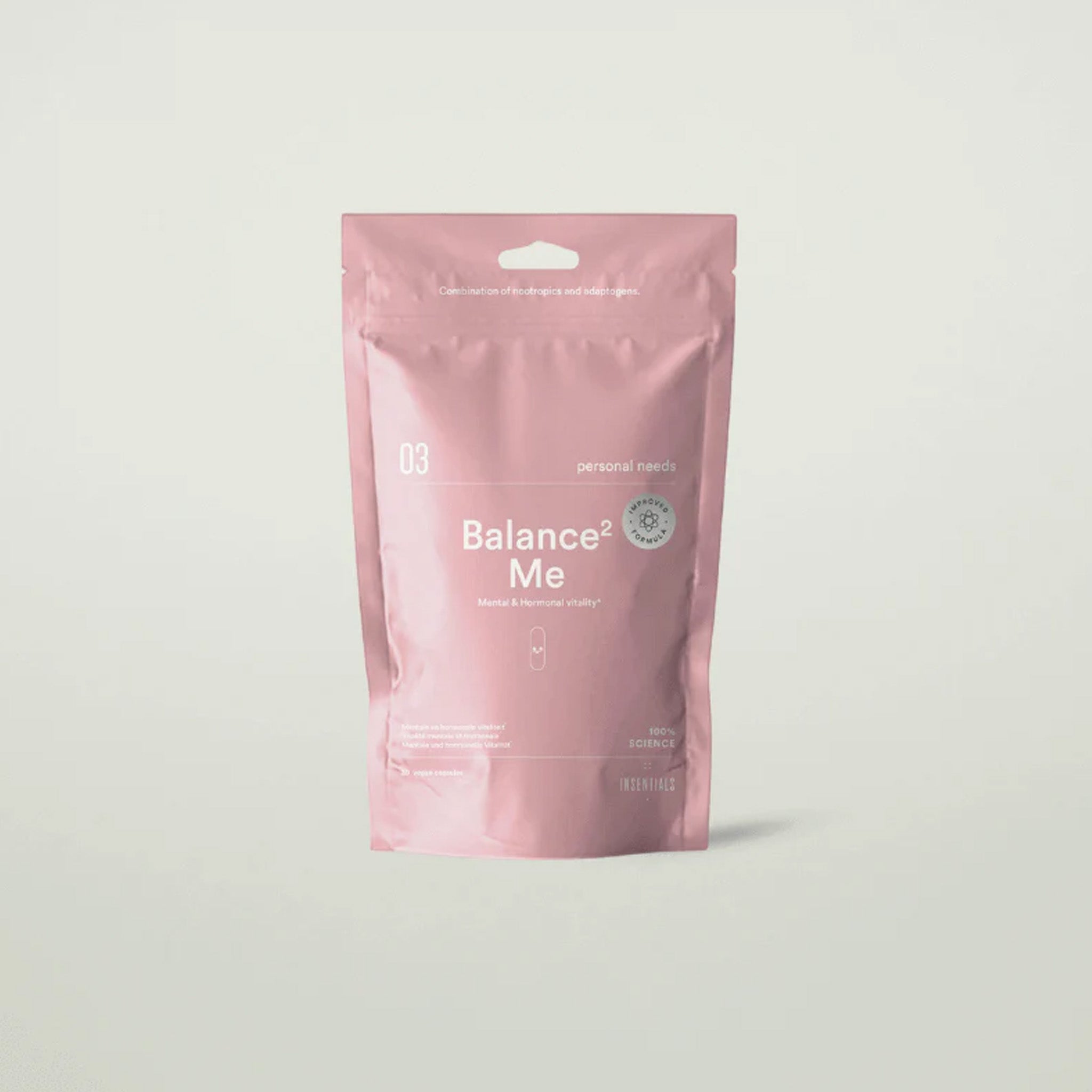 Een roze hersluitbare verpakking met het label "Insentials - Balance² Me" en witte tekst, met maca voor hormoonbalans, staat rechtop op een effen, lichte achtergrond.