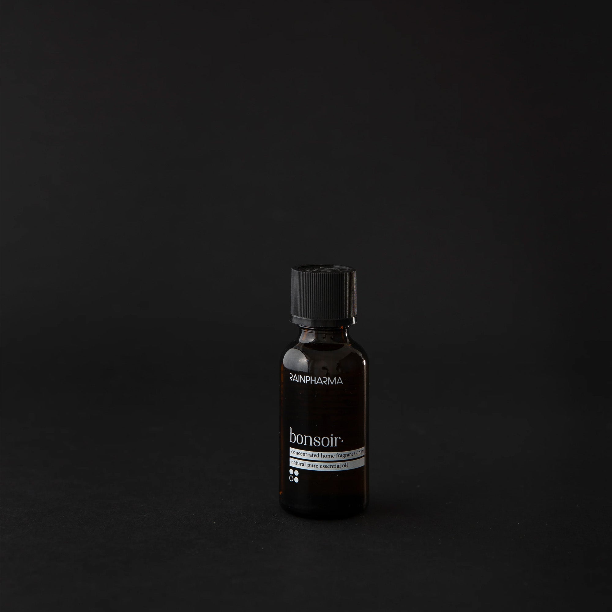 Een klein, donker flesje met het opschrift "RainPharma - Aroma Diffuser Geschenkbox Bonsoir" staat op een zwarte achtergrond, ideaal voor uw aroma diffuser.