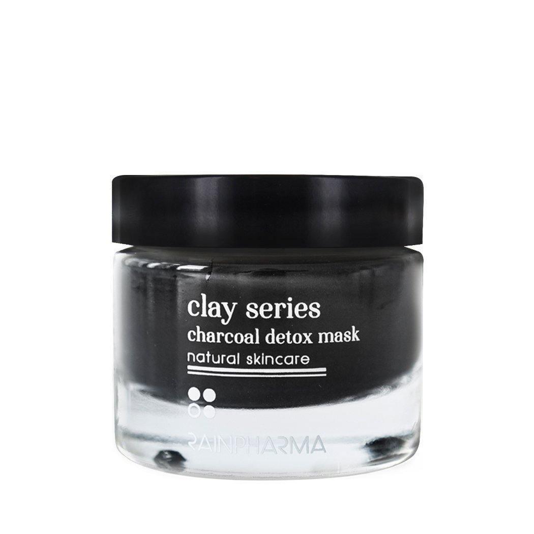 Een doorzichtige glazen pot met een zwart deksel met de tekst "RainPharma Charcoal (Detox) Mask - Zuiverend masker elk huidtype," met daarin een donker masker dat ideaal is voor alle huidtypes.