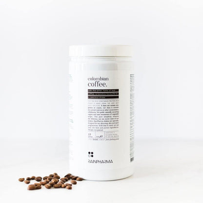 Een witte container met het opschrift &quot;Colombiaanse Coffee Shake&quot; van Rainpharma, tegen een effen witte achtergrond, met enkele koffiebonen verspreid aan de rechterkant.