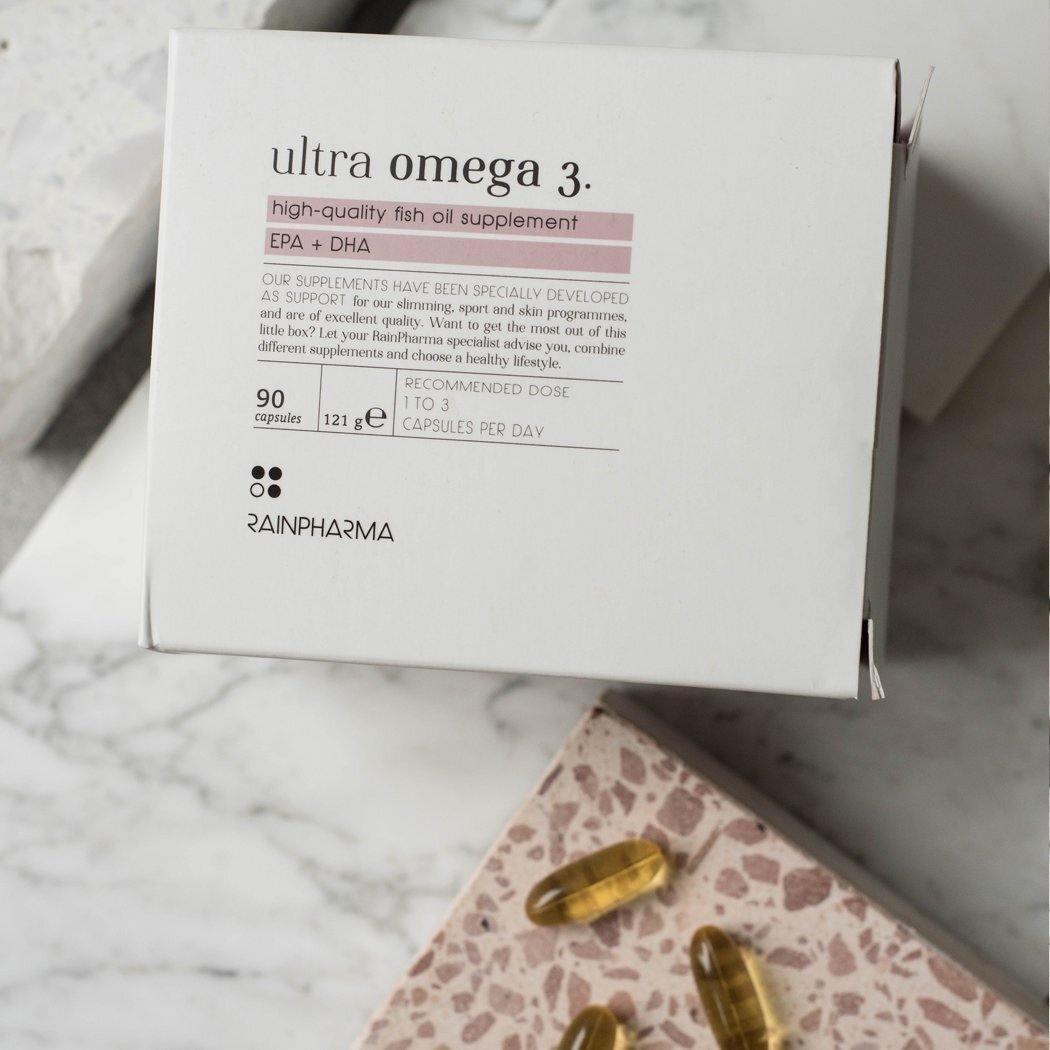 Een RainPharma Omega 3 (Ultra Omega 3) supplementendoos met drie capsules, rijk aan EPA en DHA vetzuren, uitgestald op een nabijgelegen terrazzo oppervlak.