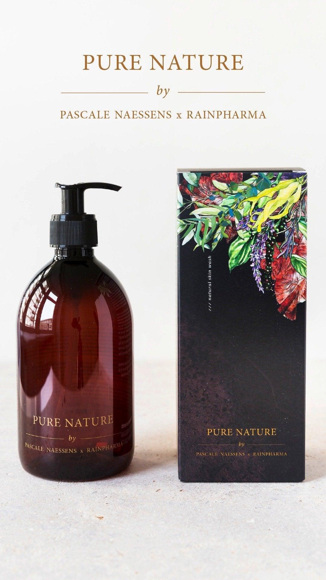 Een bruine pompflacon van RainPharma Skin Wash Pure Nature van Pascale Naessens staat naast de doos versierd met levendige botanische ontwerpen en gouden accenten - een ideale match voor je aromadiffuser.