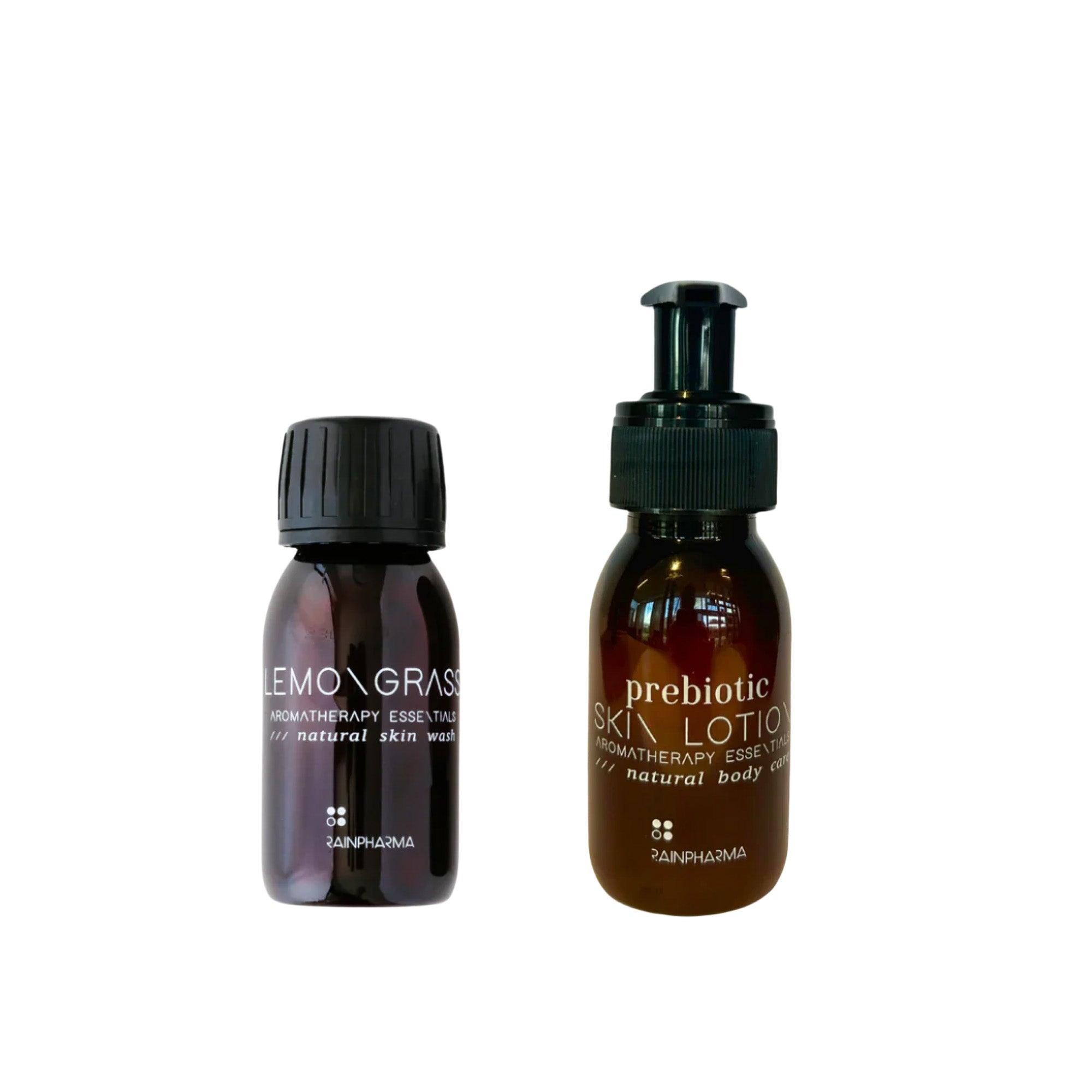 Twee bruine RainPharma-flessen met de labels "Skin Wash Lemongrass" en "Prebiotic Skin Lotion 60 ml" uit de Budget Gift Set, afgebeeld tegen een witte achtergrond.