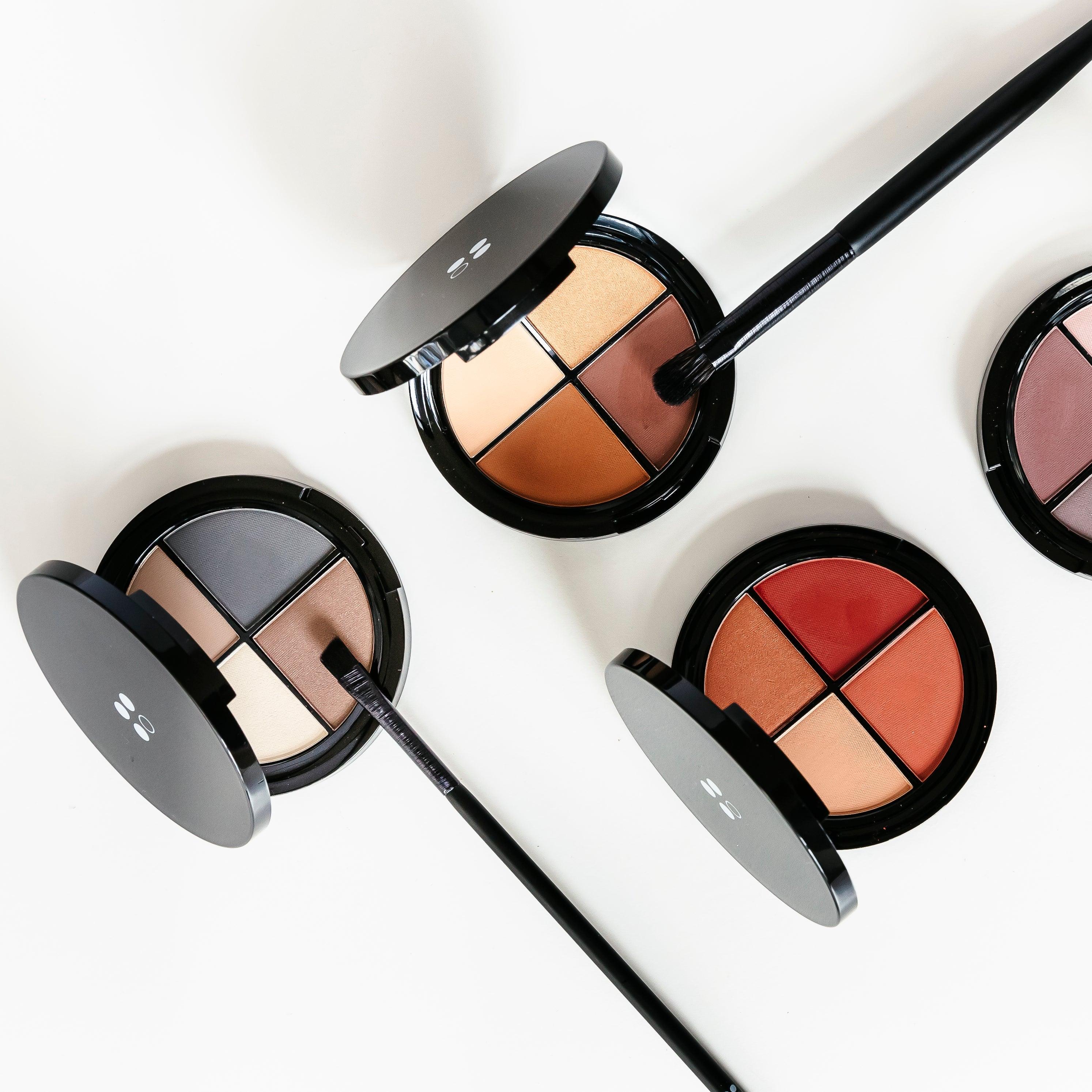 Drie ronde Puur Living make-uppaletten met elk vier natuurlijke tinten en twee kwasten worden gepresenteerd op een witte ondergrond. Ideaal als cadeau of in combinatie met het Cadeaubon Make-up verwenmoment voor twee.