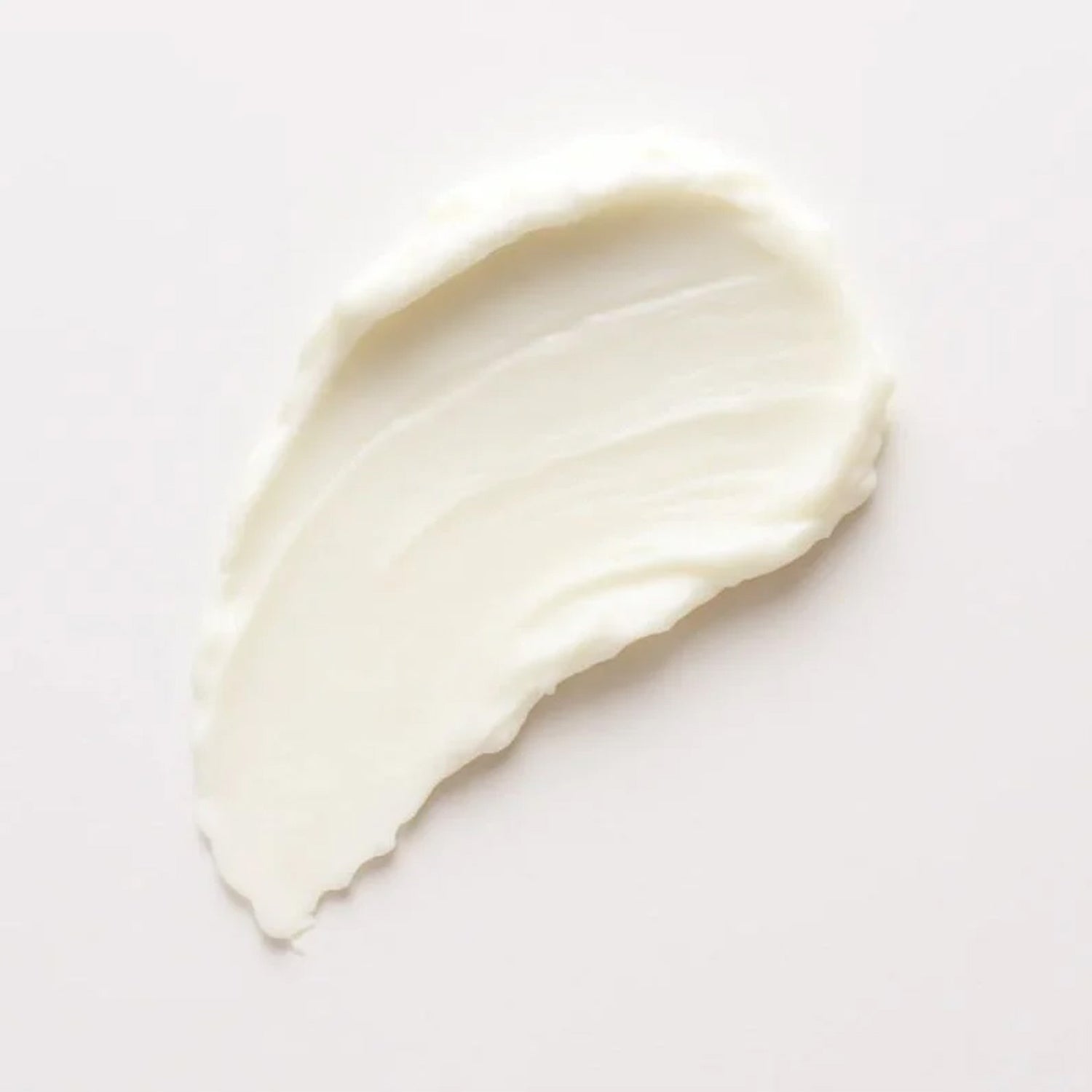 Een glad, crèmig wit laagje Ray Cica Lippenbalsem is in een gebogen vorm uitgesmeerd op een effen lichte achtergrond, klaar om droge lippen te verzachten.