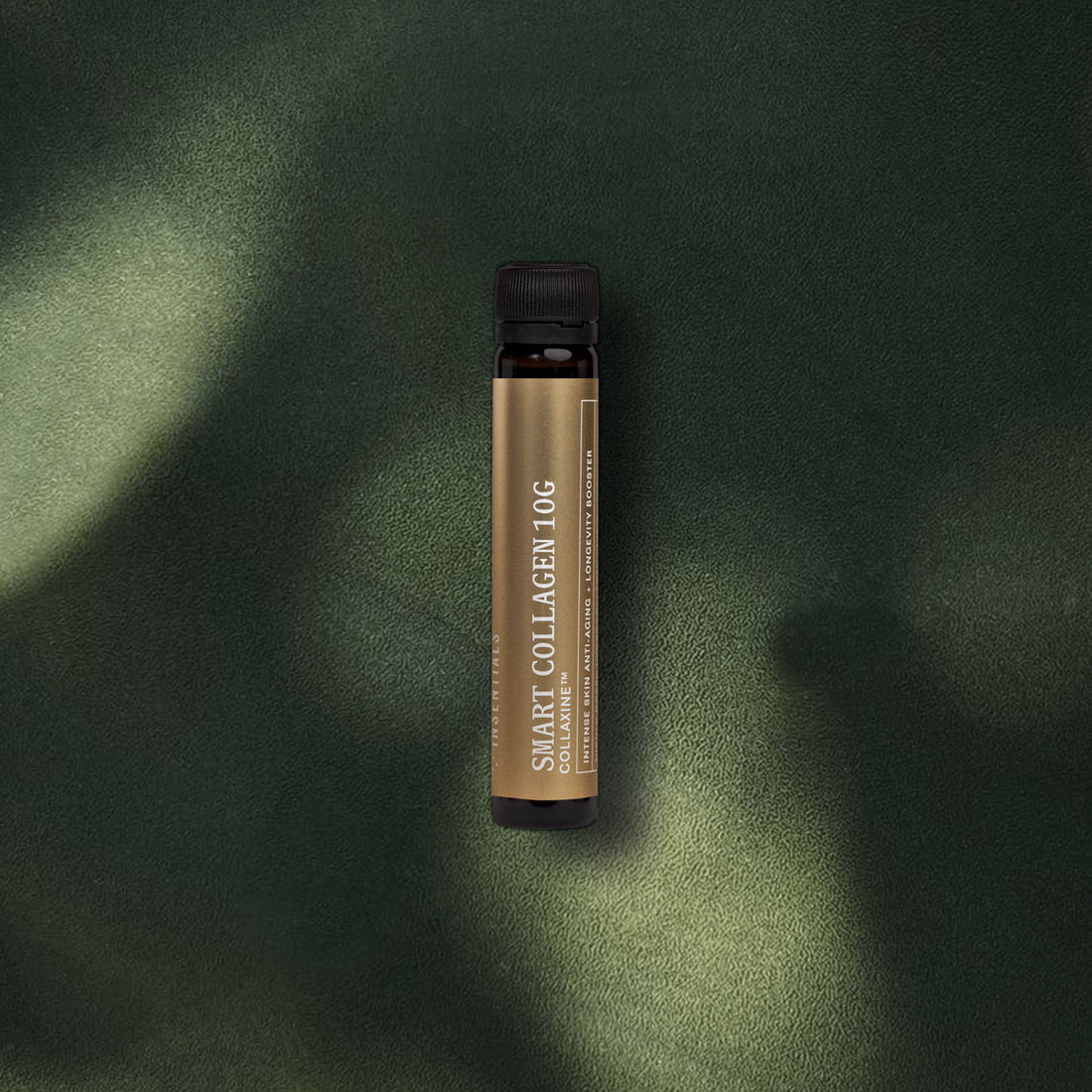 Een bruin flesje met het etiket „Smart Collagen Shot 10 g (collageen 10 g)” van Insentials staat op een donkergroen oppervlak met structuur, badend in zacht zonlicht en schaduwen – waardoor deze krachtige collageenshot voor huidelasticiteit extra goed tot zijn recht komt.
