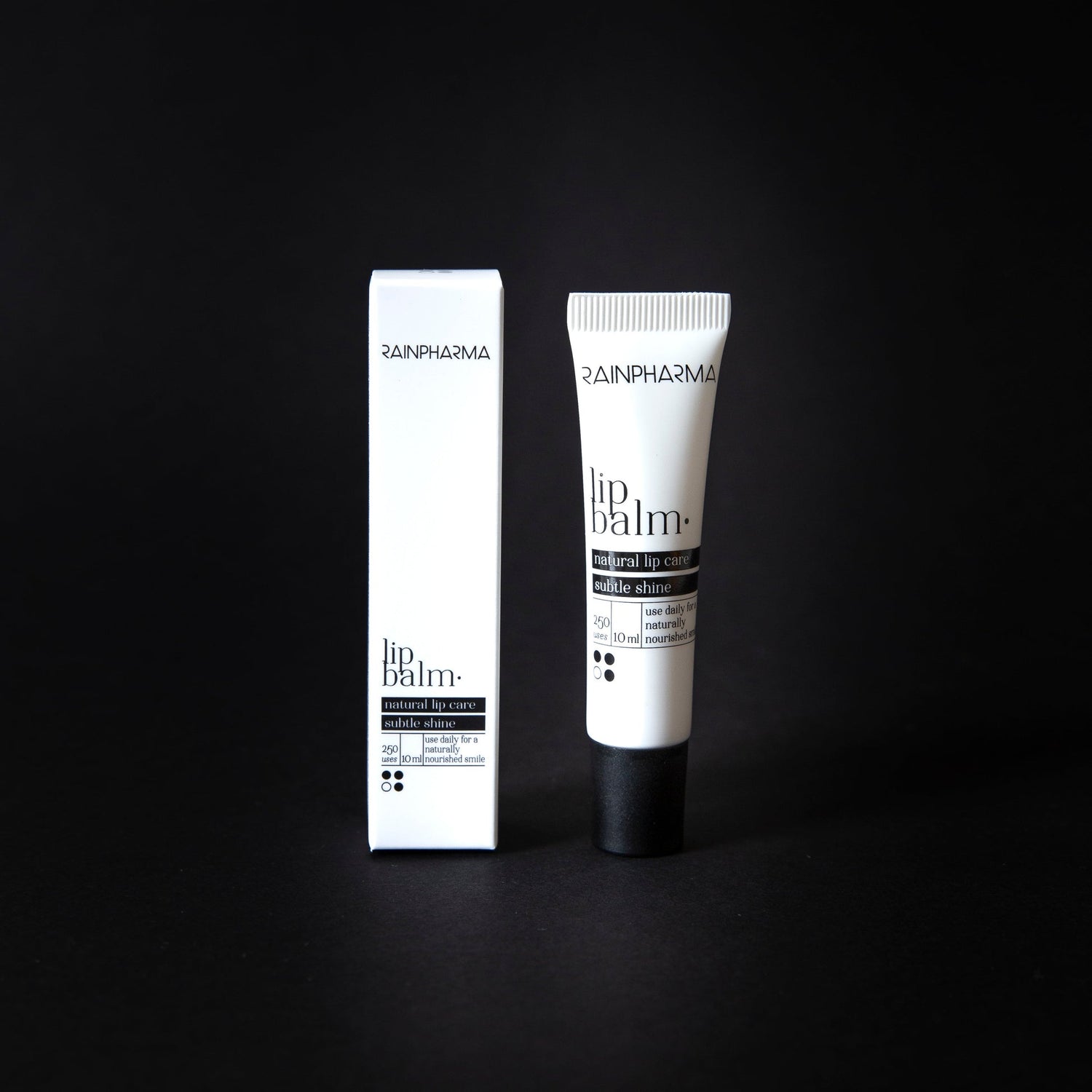 Een RainPharma lippenbalsem, verrijkt met plantaardige oliën, wordt naast de witte verpakking op een zwarte achtergrond getoond.