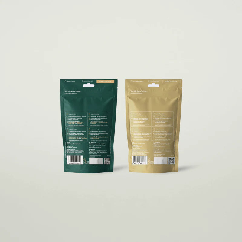 Twee rechtopstaande hersluitbare zakjes, één groen en één goud, met op de achterkant productinformatie voor Insentials Anti-Aging Pack, inclusief ingrediënten en barcodes.