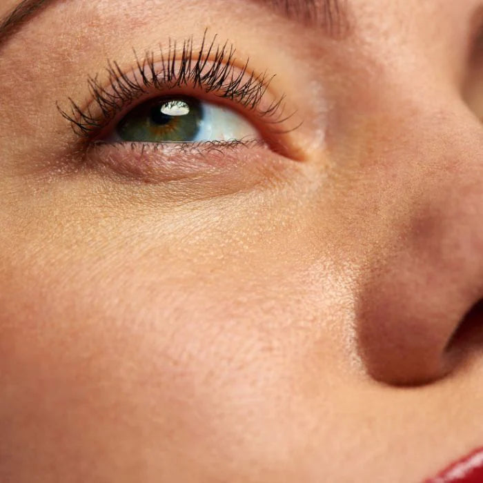 Close-up van iemands ogen, wimpers en bovenste wang, waarbij de huidtextuur en het natuurlijke licht worden benadrukt. Dit is perfect om de hydraterende effecten van Insentials Anti-Aging Pack te laten zien.