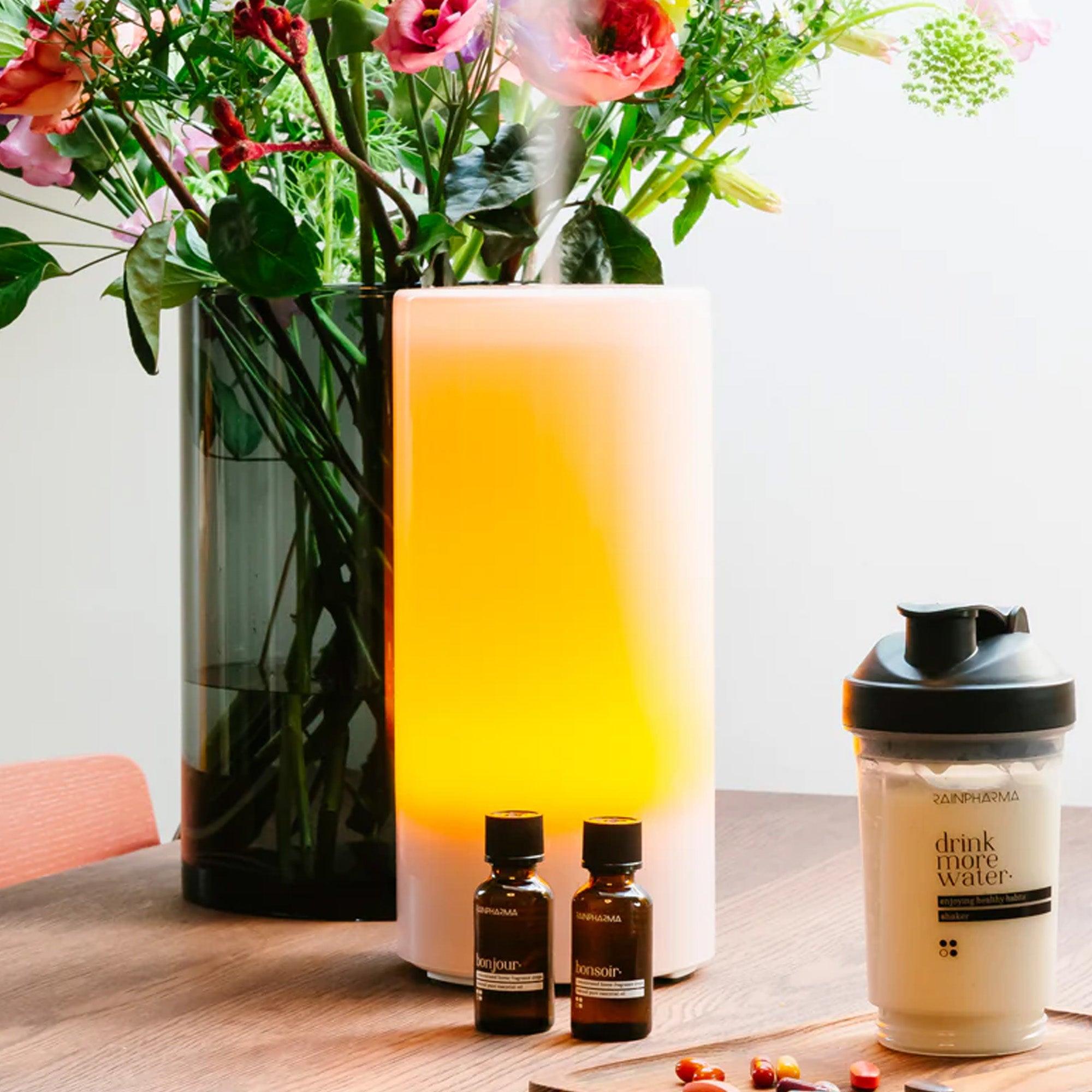 Een vaas met kleurrijke bloemen, een verlichte diffuser met een flesje etherische olie van 30 ml van RainPharma&
