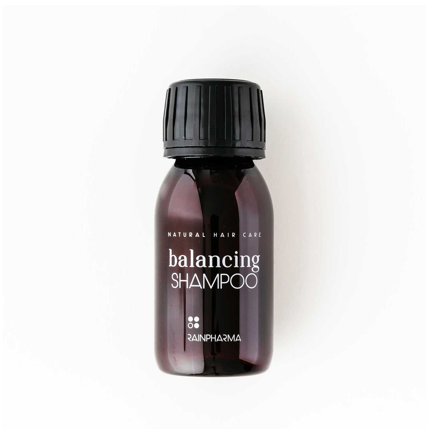 Een kleine bruine plastic fles RainPharma Balancing Shampoo voor de gevoelige hoofdhuid, gelabeld en voorzien van een zwarte schroefdop, is afgebeeld tegen een witte achtergrond.